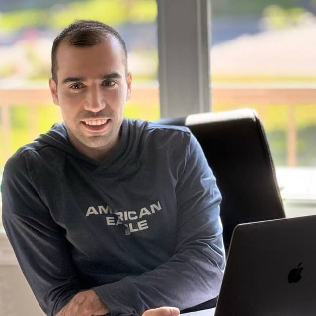 Mohammad Mohajer, full-stack developer and tech mentor, coding at his desk with a laptop.